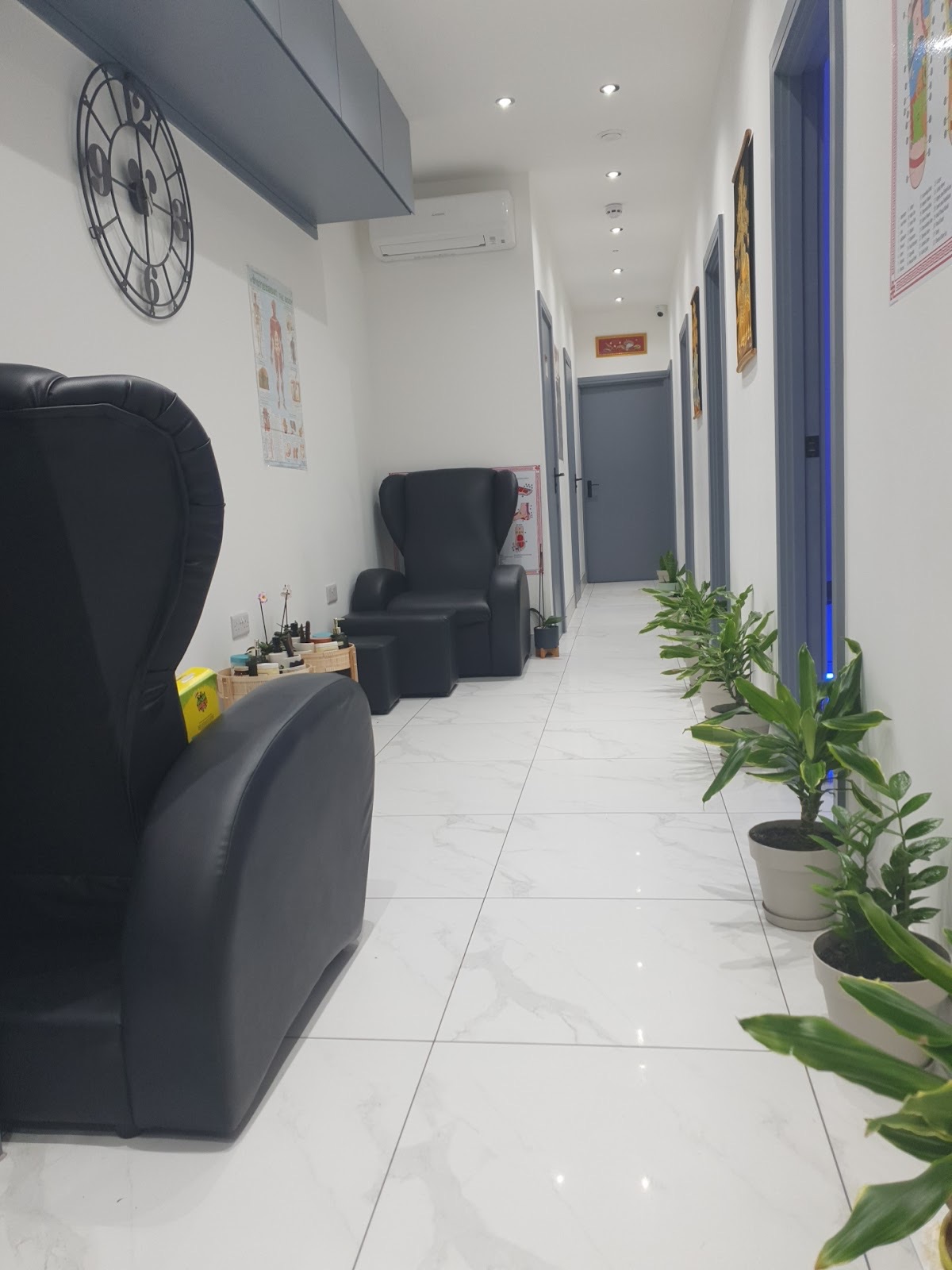 The treatment corridor at Charoensap Thai Massage, with reclining chairs, marble floor and potted plants